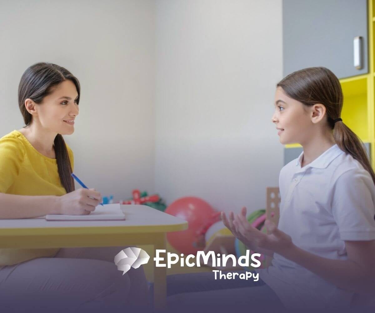ABA therapist and a child engage in a conversation while sitting at a table during ABA therapy.