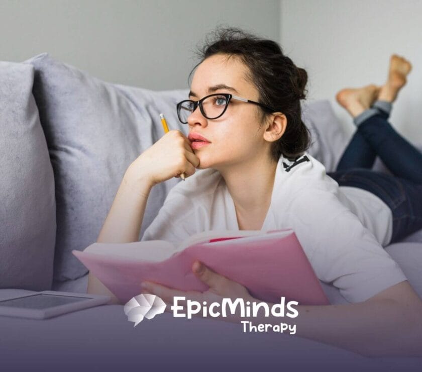 A young woman on the autism spectrum with glasses lies on a couch.
