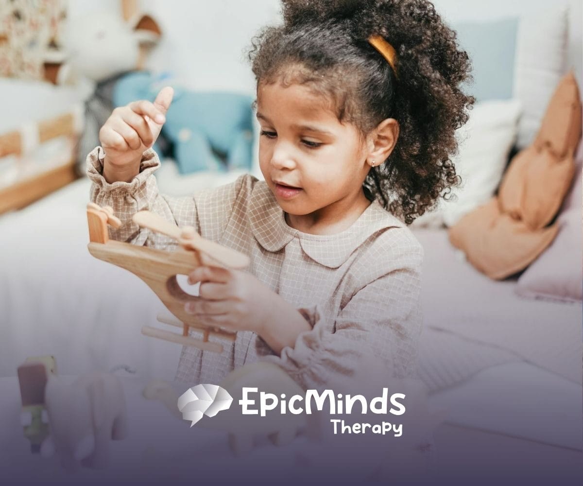 An autistic girl holding and inspecting a wooden toy helicopter at a table during ABA therapy in MD.