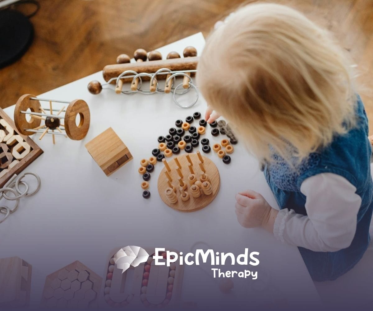 An autistic toddler playing with wooden Montessori toys on a white table during in-home ABA therapy in North Carolina.