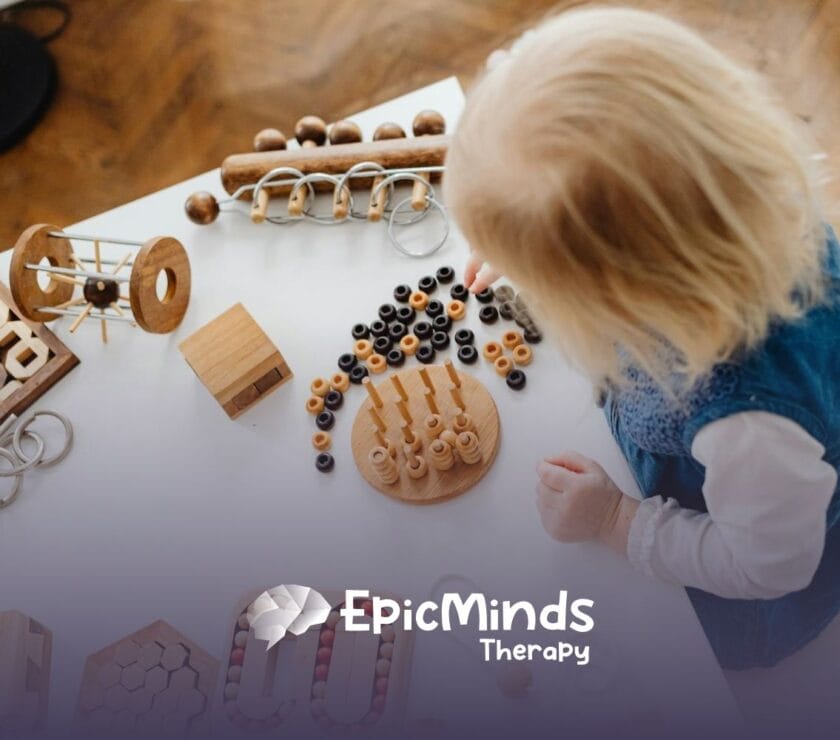 An autistic toddler playing with wooden Montessori toys on a white table during in-home ABA therapy in North Carolina.