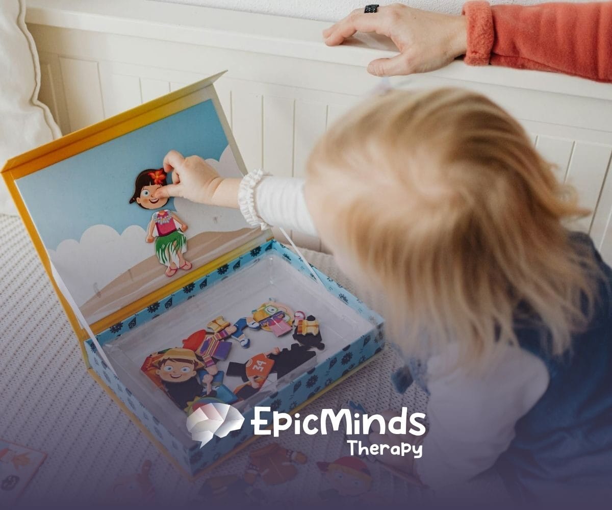 An autistic toddler playing with a magnetic dress-up doll set on a bed during in-home ABA therapy in North Carolina.