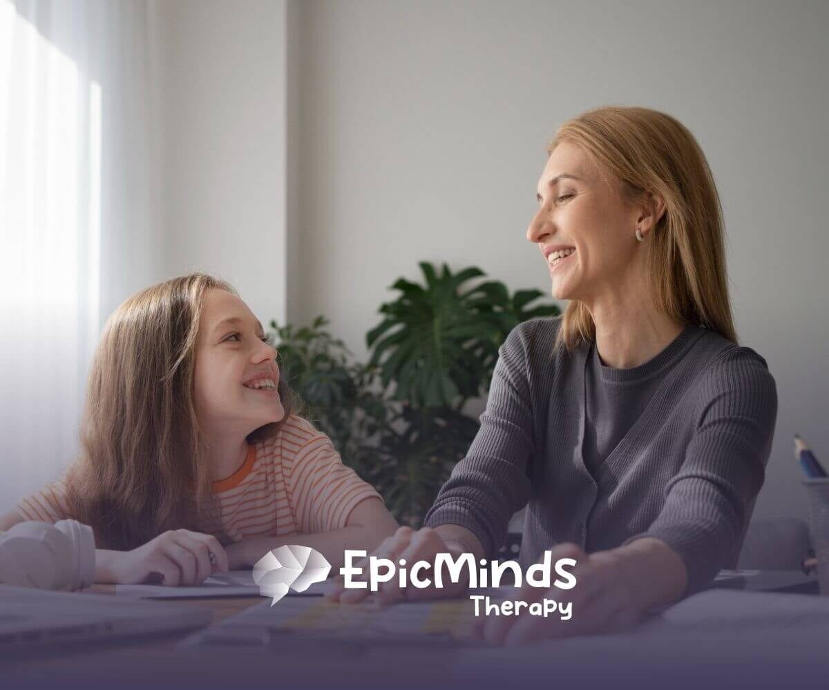 An ABA therapist and autistic girl smile at each other while doing an activity in ABA therapy.