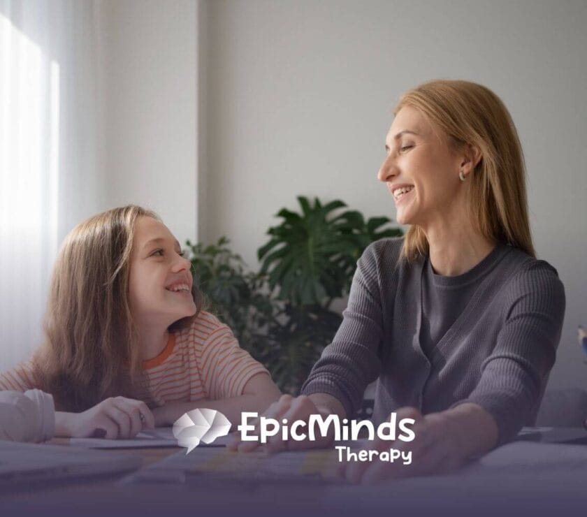 An ABA therapist and autistic girl smile at each other while doing an activity in ABA therapy.