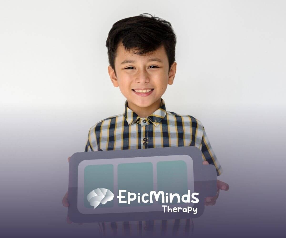 Smiling boy with autism holding a paper cutout of a battery symbol.