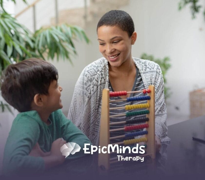 Smiling BCBA teaching young boy with an abacus in ABA therapy.