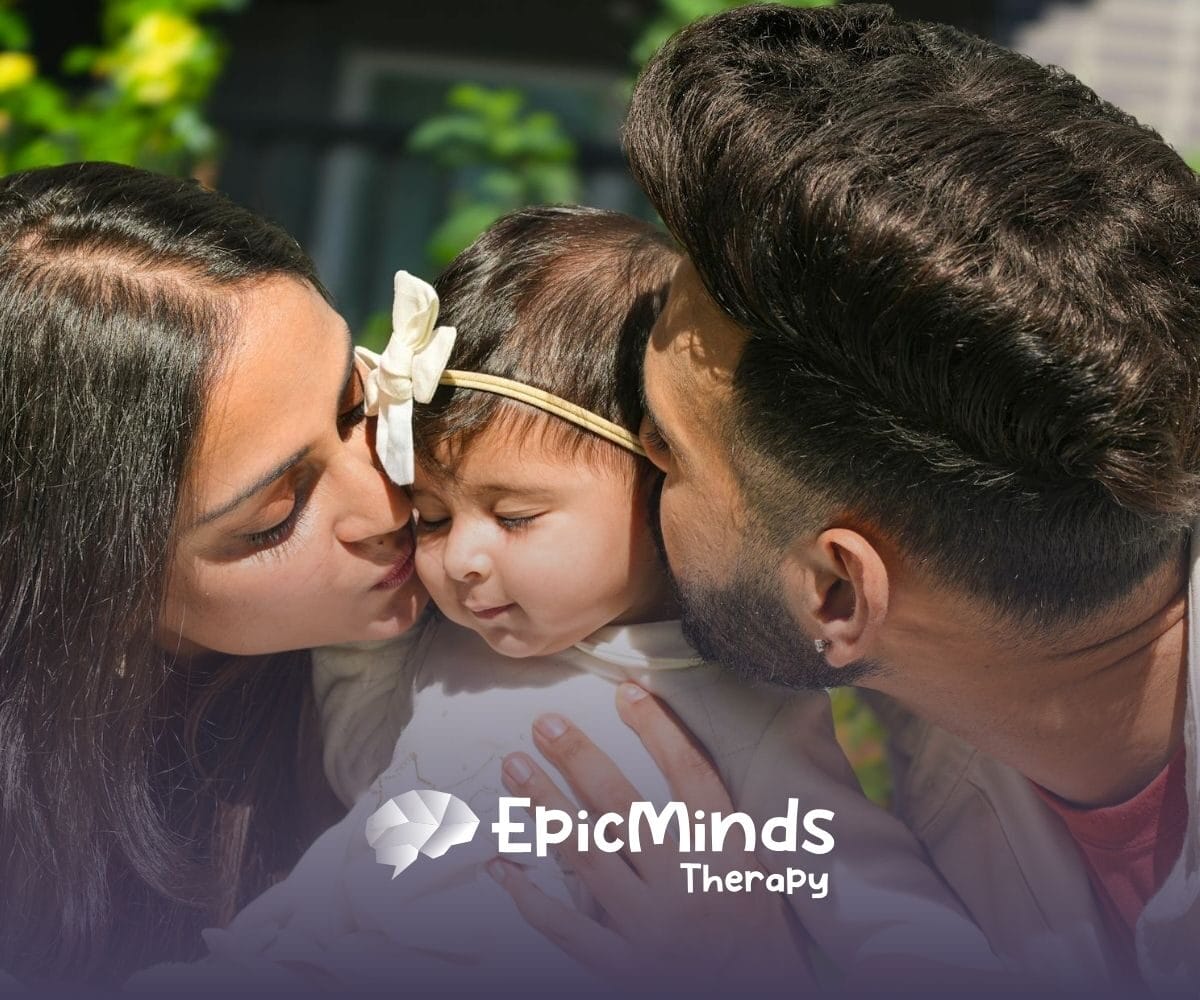 Mom and dad kiss their baby’s cheeks outside, sharing a sweet moment of love and connection in North Carolina.