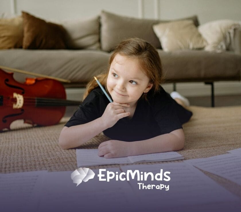 An autistic girl lying on the floor, smiling while writing music notes beside a cello during ABA therapy in NC.
