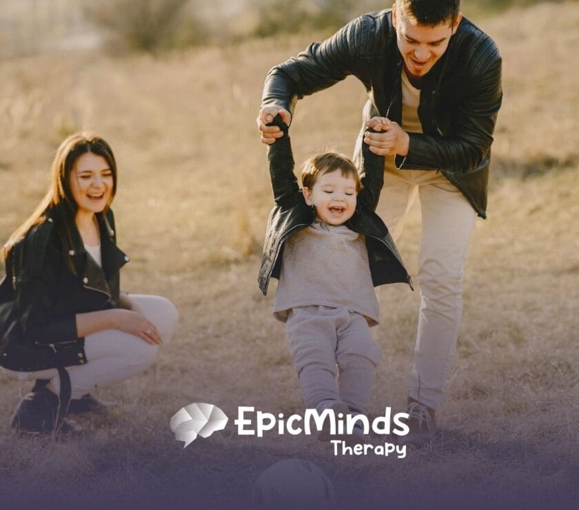 Mom and dad kick a ball with their giggling child in a grassy field on a sunny afternoon in North Carolina.