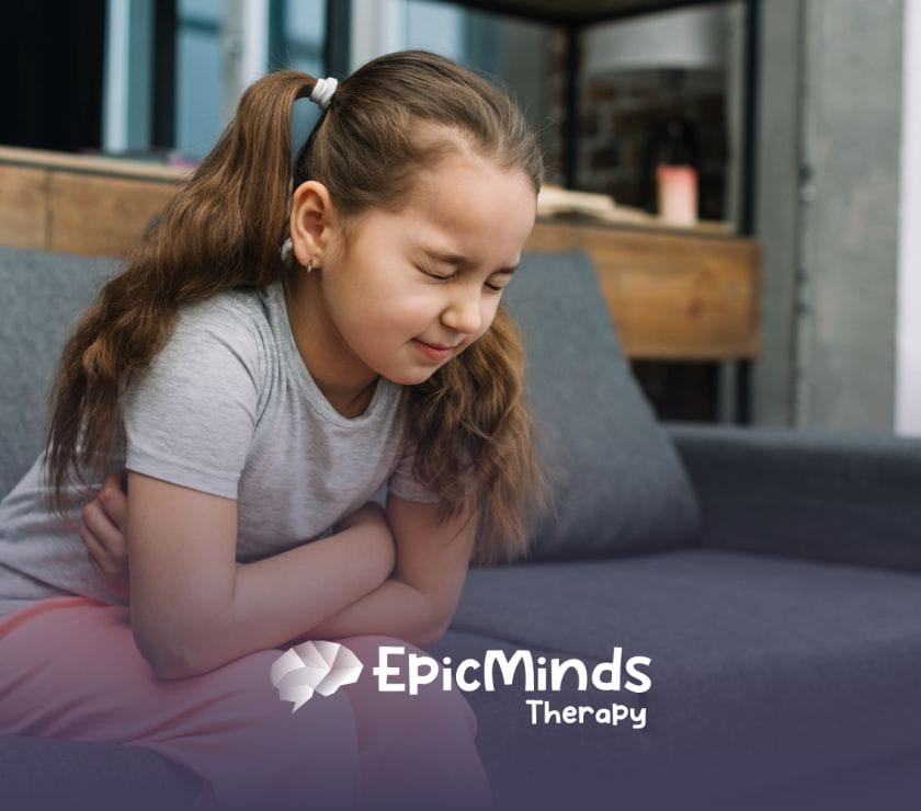 A child sitting on a bench, with her arms wrapped around her stomach