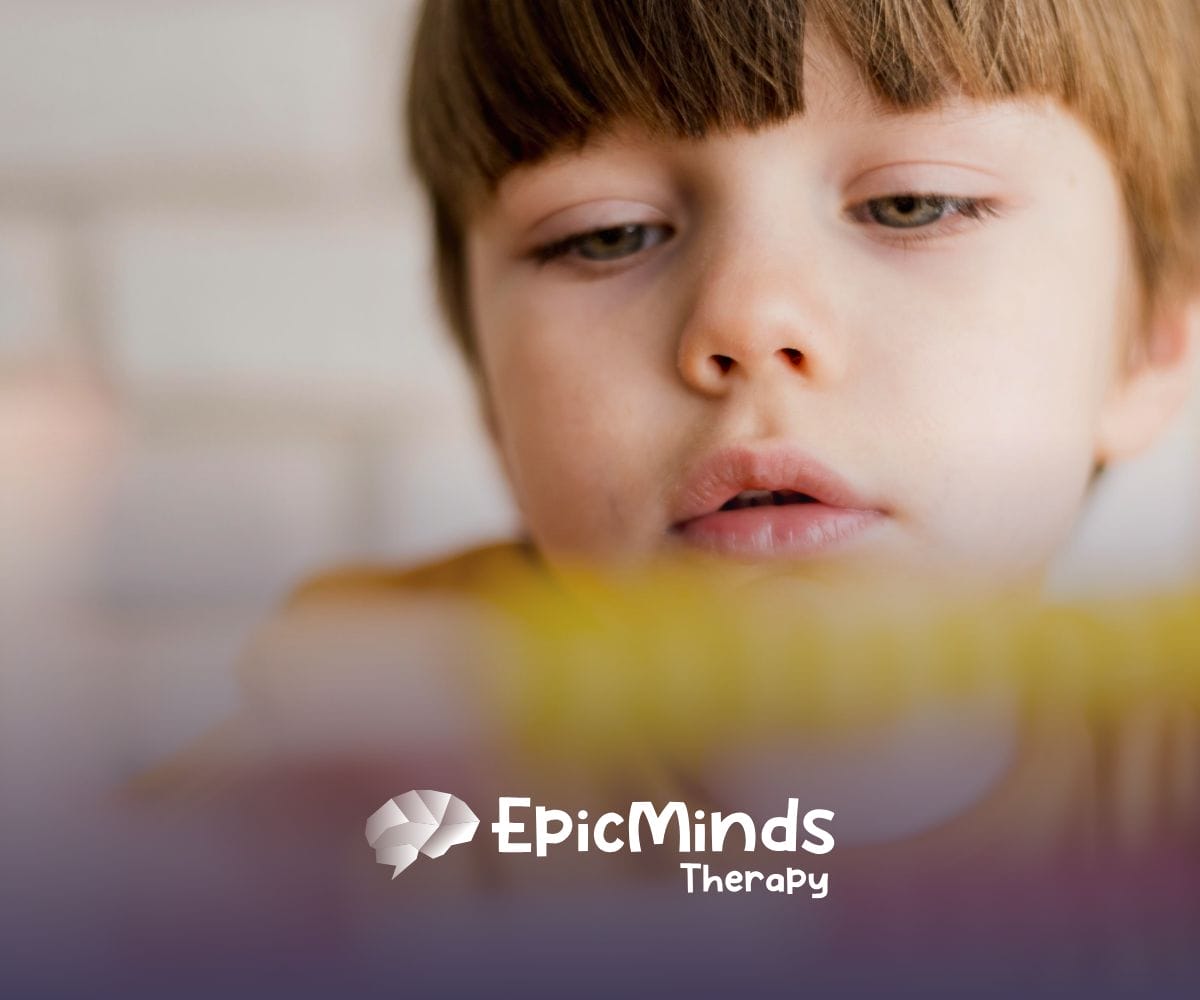 A kid with low-functioning autism looking at a toy